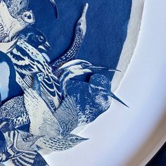 blue and white artwork with birds in the middle on a paper plate next to scissors