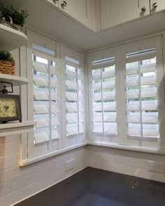 an empty room with white shuttered windows and a clock on the shelf next to it