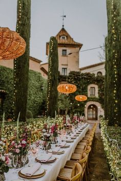 a long table set up with plates and place settings for an outdoor dinner in the garden