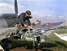 two men working on an airplane in the grass