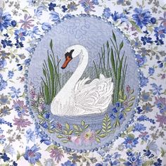 a white swan sitting on top of a blue and purple flowered wallpaper covered in flowers