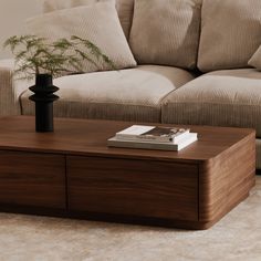 a coffee table with a book on it in front of a couch and sofa behind it