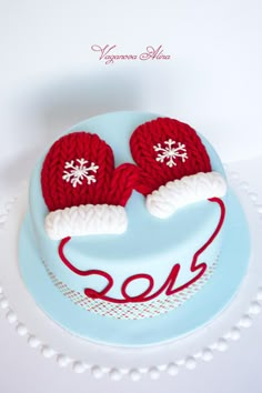 a cake decorated with two knitted mittens on top of a blue frosted surface