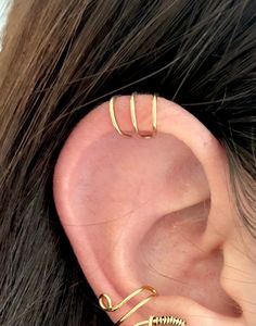 a woman wearing two gold ear cuffs and an ear cuff