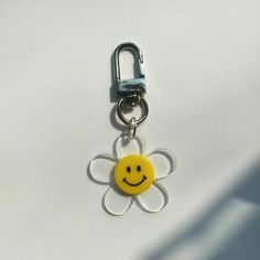 a smiley face keychain hanging from a metal hook on a white table top