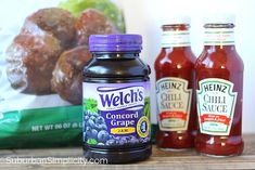 two bottles of ketchup and some other condiments on a wooden table