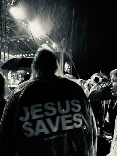 black and white photograph of people walking in the rain with jesus saves jacket over their shoulders