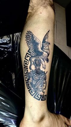 a man's arm with an eagle and crest tattoo on the left side of his arm