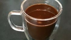 a glass mug filled with liquid sitting on top of a table