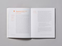 an open book with white pages and orange lettering on the front, sitting on top of a gray surface