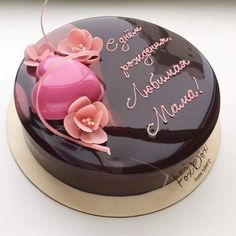 a chocolate cake with pink flowers and writing on the top that says congratulations to someone