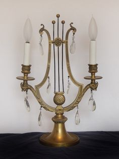 an antique brass candelabra with three candle holders and crystal drops hanging from it