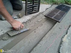 a man is working on cement with a grate