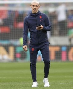 a man standing on top of a soccer field holding a cell phone in his hand