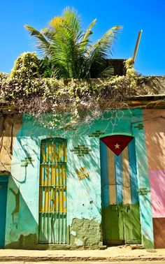 an old building with colorful doors and palm trees on the top of it's roof