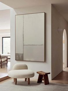 a white chair and ottoman in a room with a mirror on the wall above it