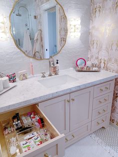 a bathroom with a sink, mirror and drawers in the middle that are open to reveal various items