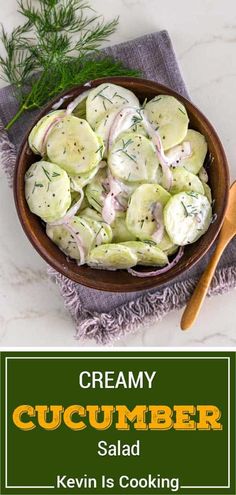 a bowl filled with cucumber salad next to a wooden spoon