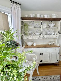 a white china cabinet with lots of dishes on it's shelves in a living room