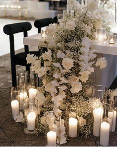 a table topped with lots of white flowers and candles