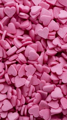 pink heart shaped candies are scattered on top of each other