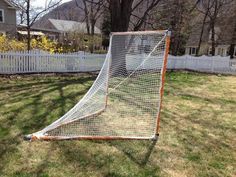 an old goalie net in the yard next to a white picket fence