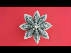 a dollar bill origami flower on a pink background