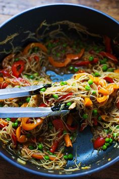 a pan filled with noodles and vegetables on top of a wooden table