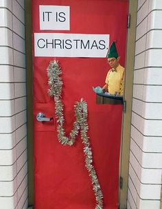 a red door decorated with tinsel garlands and a elf on it's head