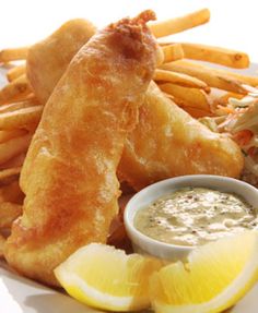 fried fish with dipping sauce and lemon wedges