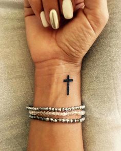 a woman's wrist with a cross tattoo on it and two different bracelets