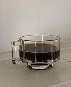 a glass cup filled with liquid sitting on top of a white counter next to a wall