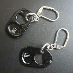 two metal key chains with black keys attached to each other on top of a table