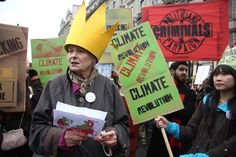 a group of people holding protest signs and wearing crowns on their heads while standing next to each other