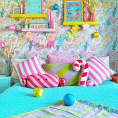 a bed with colorful pillows and pictures on the wall next to it in a bedroom