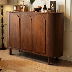 a large wooden cabinet sitting on top of a hard wood floor next to a lamp