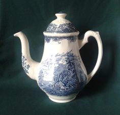 a blue and white porcelain teapot on a green background