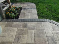 an outdoor patio with brick pavers and flowers in the planter box next to it