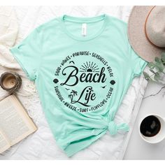 Beach Life T-Shirt, Beach Shirt, Beach Shirt, Beach Vibes Shirt, Beach Days T-Shirt, Bestie Beach Shirt, Summer Tee, Summer beach shirt How to Order?  1-Choose your t-shirt color, 2- Choose your size, 3- Select the quantity, 4- Click Add to Cart.  Production and shipping: * 100% airlume combed and ring-spun cotton, 32 singles 4.2 oz. * Solid colors are %100 cotton * Heathers are %52 cotton %48 polyester * Athletic Heather is combed and ring-spun cotton, 10% polyester * Seamless collar * Heat tra Tropical Graphic Print T-shirt For Beach, Green Letter Print T-shirt For Vacation, Summer Hawaiian Shirt With Letter Print, Pre-shrunk Graphic Tee For Beach Season, Short Sleeve Shirt For Beach Party Vacation, Vacation Beach Shirt With Palm Tree Print, Summer Beach Camp Shirt With Graphic Print, Summer Beach Shirt With Palm Tree Print, Summer Shirt With Palm Tree Print For Beach