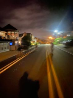 a blurry photo of people riding bikes down the street at night time with buildings in the background