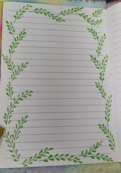 an open notebook with green leaves on it and lined paper in the bottom right corner