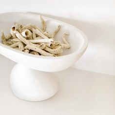 a white bowl filled with sticks on top of a table