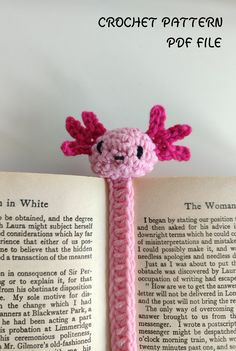 a pink crocheted bookmark with a smiling face on top of an open book