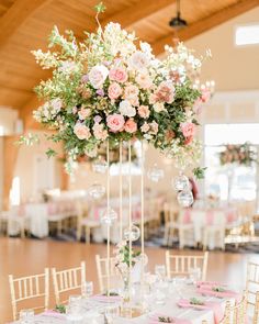 an elegant wedding reception with pink and white flowers in tall centerpieces on tables