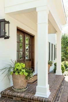 a white house with a potted plant on the front porch