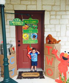 a young boy standing in front of a door with cardboard boxes on the ground and sesame street signs