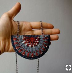 a hand holding a small purse with chains attached to it's sides and beads on the outside