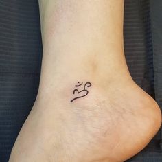 a small tattoo on the foot of a woman's left foot, with an omen symbol