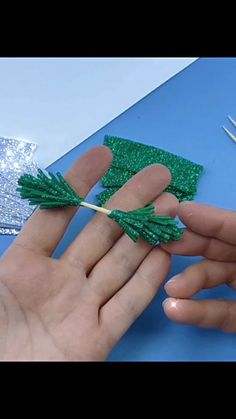 someone is making something out of green string and plastic straws on a blue table