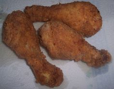 three fried chicken pieces sitting on top of a piece of paper